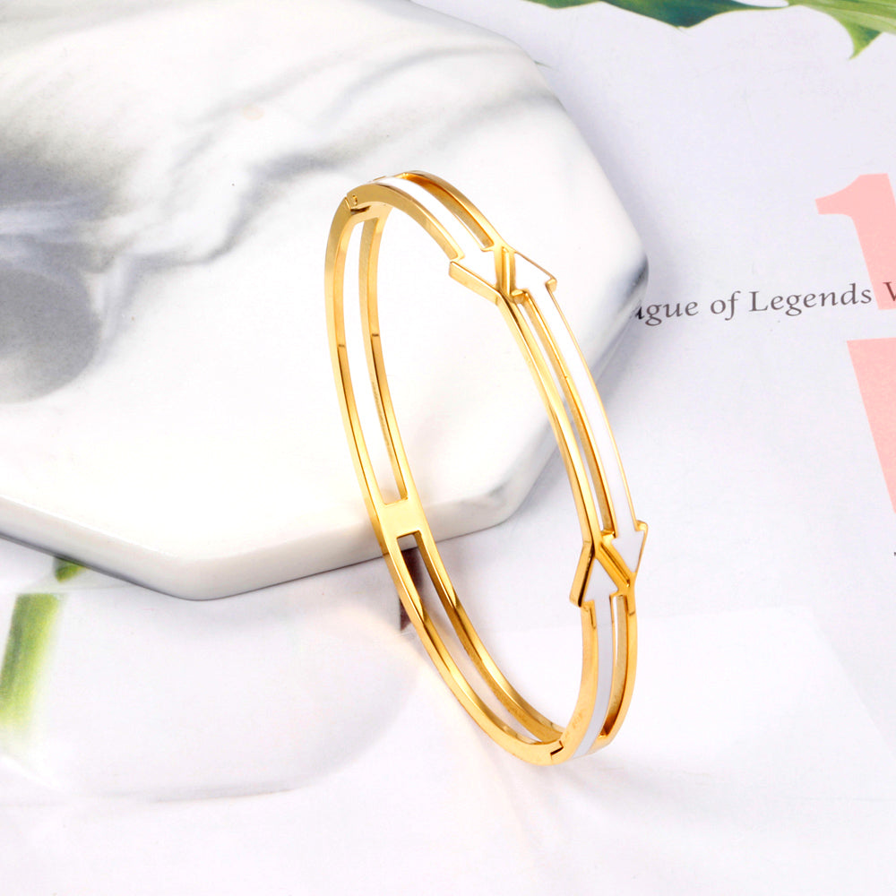 Gold colored hard bracelet with directional arrows with oil dripping in the center white color asonjewelry