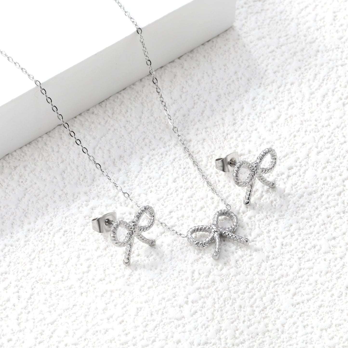 Bow Set Steel Color Earrings:13.2*11.2mm Necklace:13.2*11.2mm0.3 Cross Chain*40+5cm+6mm Round Plaque asonjewelry