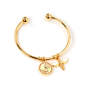 Gold colored hard bracelet with flower and butterfly charm