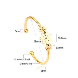 Gold colored hard bracelet with three small flowers of different sizes
