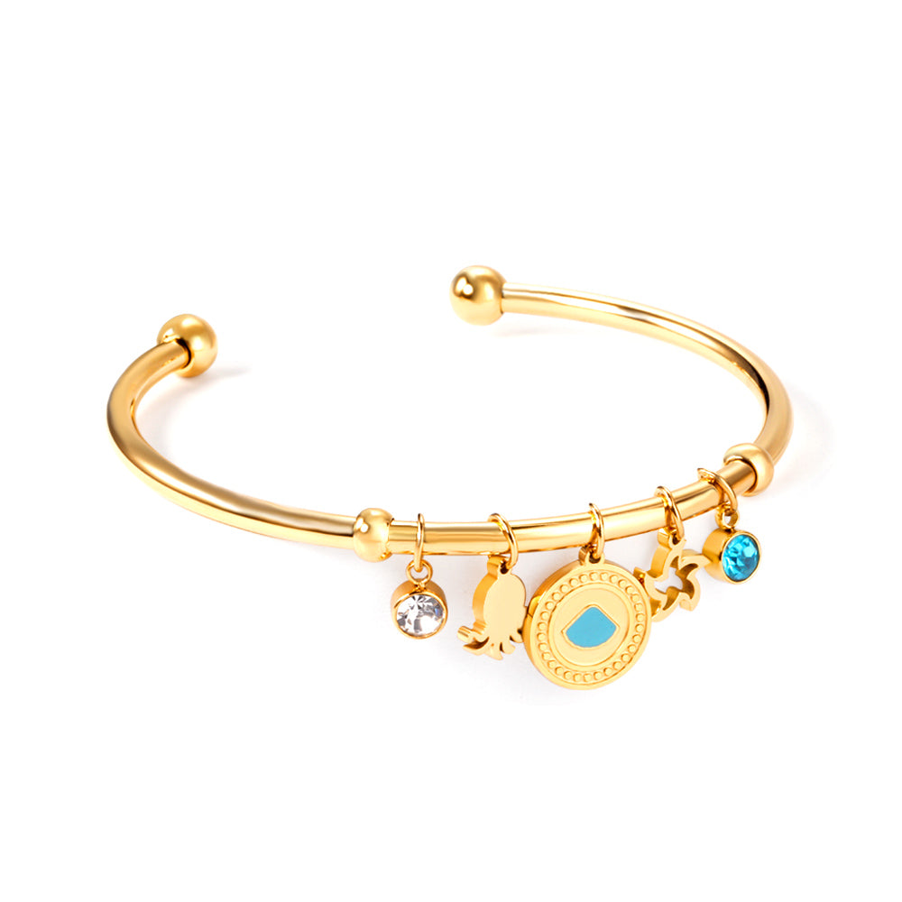 Gold bangle with two diamonds of different colors and a charm with a scallop on the door of the discus. asonjewelry