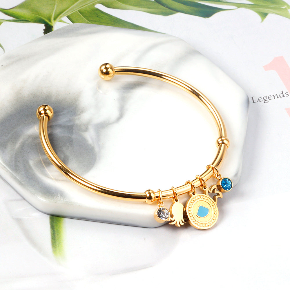 Gold bangle with two diamonds of different colors and a charm with a scallop on the door of the discus. asonjewelry